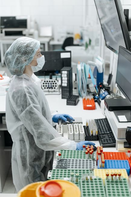 A female scientist in protective gear analyzing samples in a modern laboratory setting.