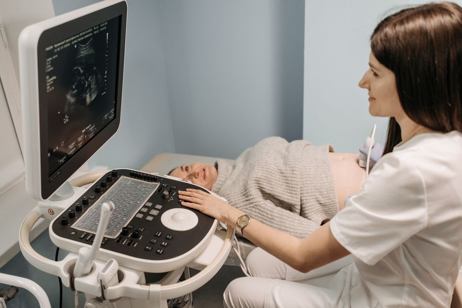 A healthcare professional performing an ultrasound on a pregnant woman in a clinic setting.
