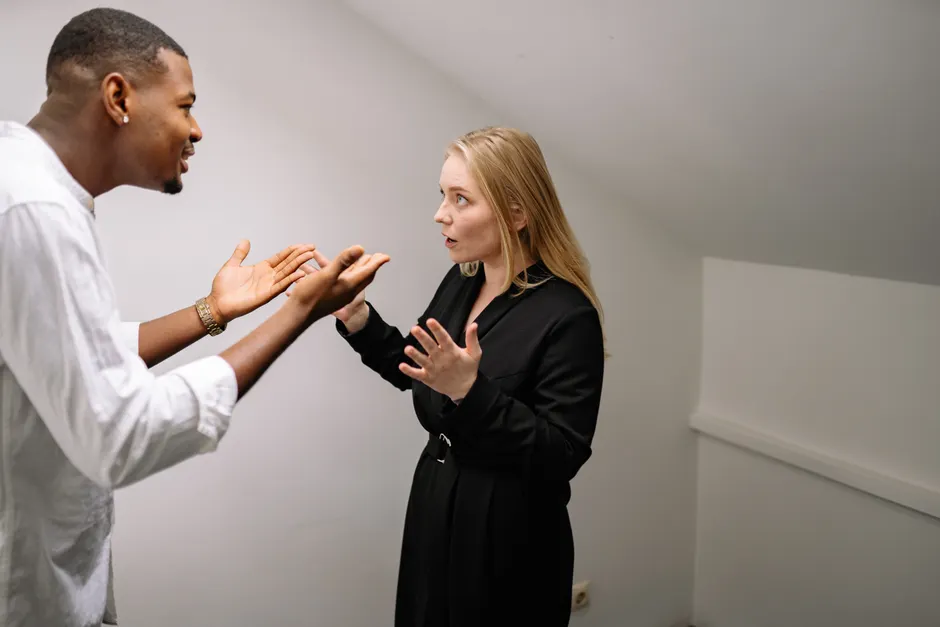 Désamorcer une dispute : 7 phrases pour sortir du bras de fer A man and woman having a heated discussion in a minimalistic indoor space.