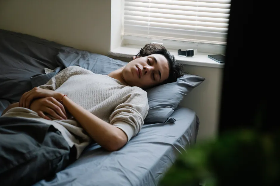 Mieux dormir et santé mentale : ce que montrent les travaux de 2026 A man calmly sleeps on a bed in a cozy bedroom with soft lighting.