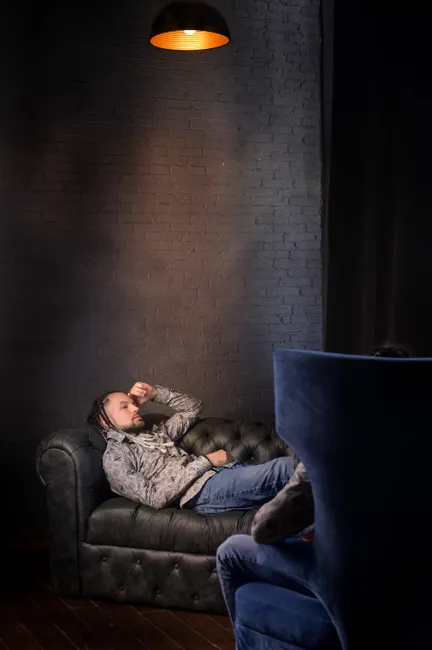 A man lying on a sofa under soft lighting in a cozy room.