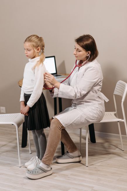 A pediatrician conducting a health checkup on a child in a clinic setting.