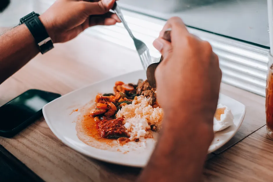 Émétophobie : quand la peur de vomir rétrécit la vie A person enjoying a meal of rice and assorted dishes at a restaurant by the window.