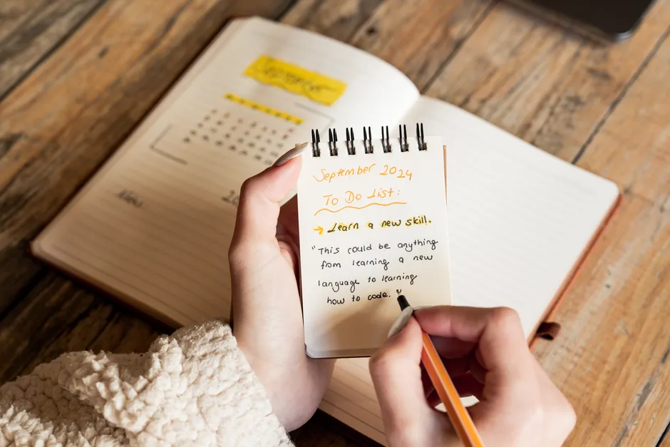 Rétablissement dans la schizophrénie : distinguer symptômes, autonomie et vie choisie A person writes a September 2024 to-do list in a notebook, focusing on learning new skills.