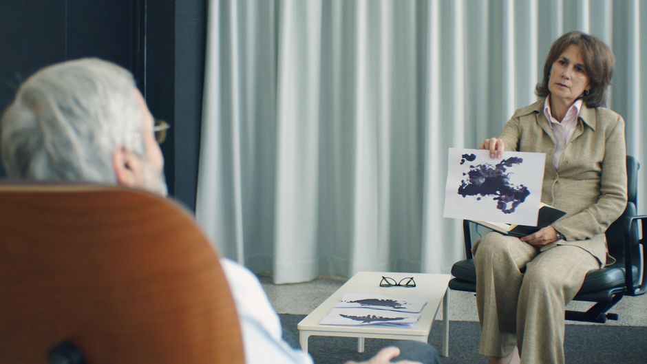 A therapist and patient in a psychotherapy session, discussing inkblot test results.