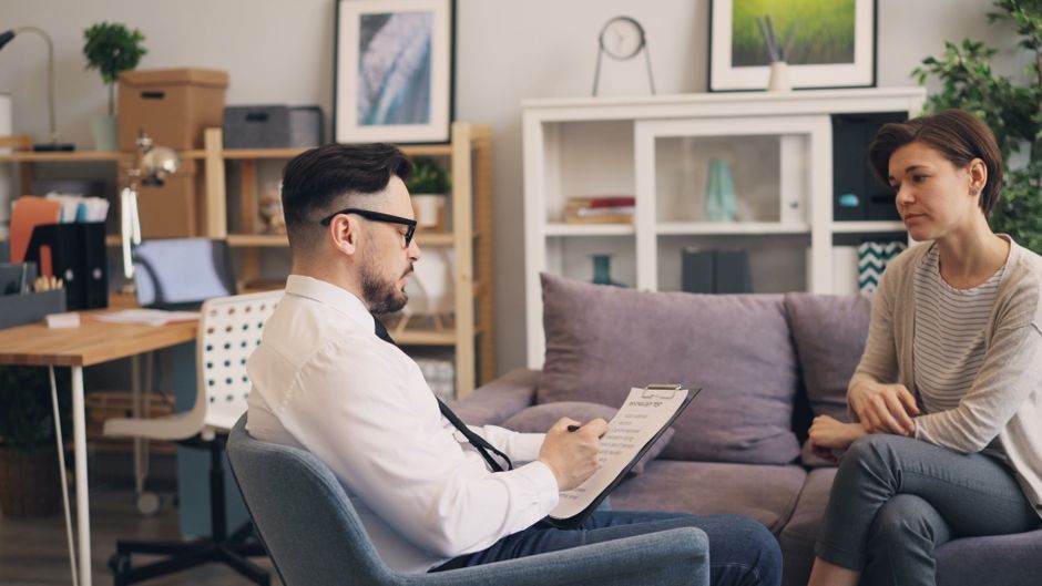 A therapist engages in a consultation session with a female patient in a cozy office setting.