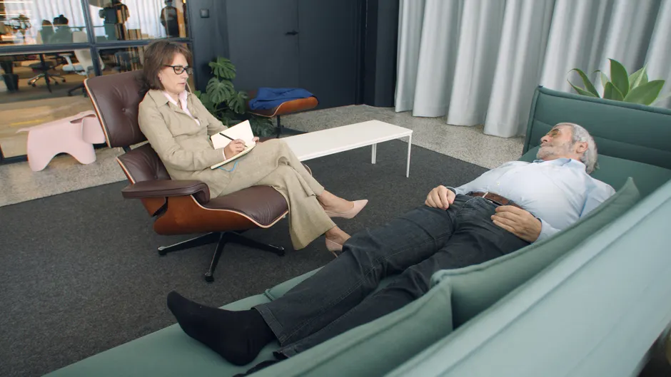 A therapist taking notes while a patient lies on a sofa during a counseling session.