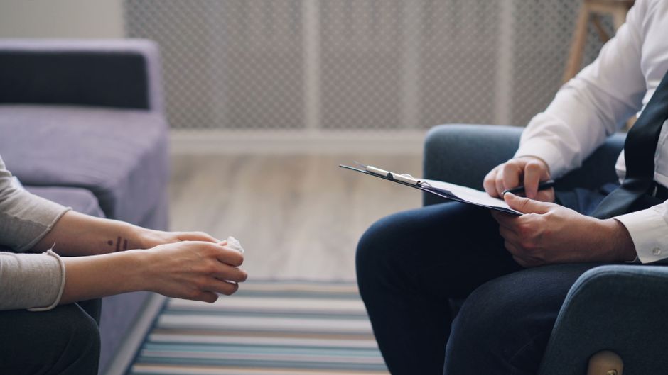 A therapy session with a psychologist and patient, discussing mental health indoors.