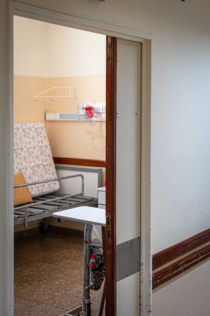 A view into an empty hospital room featuring a single bed and medical equipment, conveying healthcare and recovery.