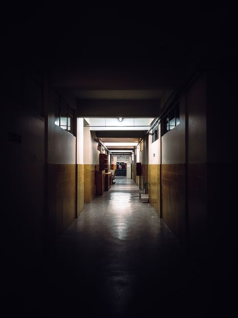 A view of a dimly lit corridor in an empty school building, capturing a moody atmosphere.