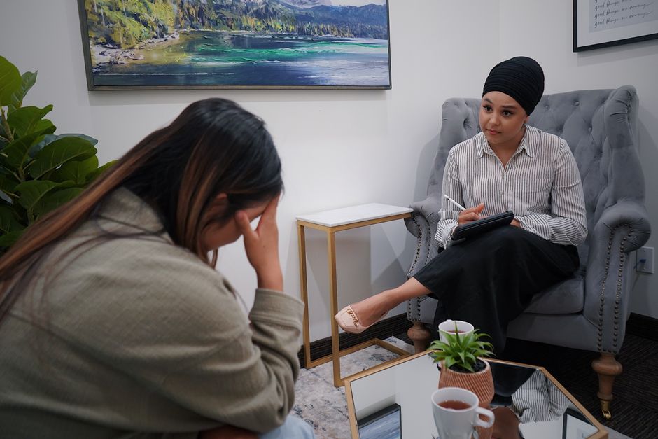 Regretter ses hallucinations auditives : quand aller mieux ressemble à un deuil A woman discusses personal issues in a therapy session with a professional counselor.