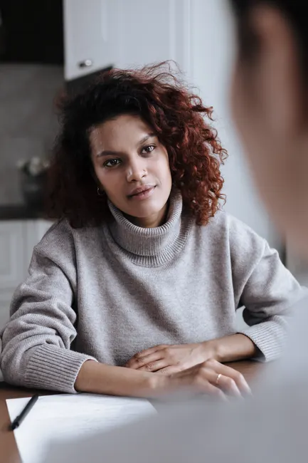 A young woman attentively listening and engaging in a conversation indoors.