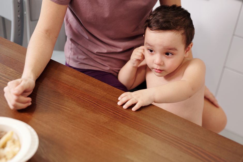 ARFID chez l’enfant : quand le picky eating dépasse le simple refus Adorable young child reaching towards food on a table with a parent's support.