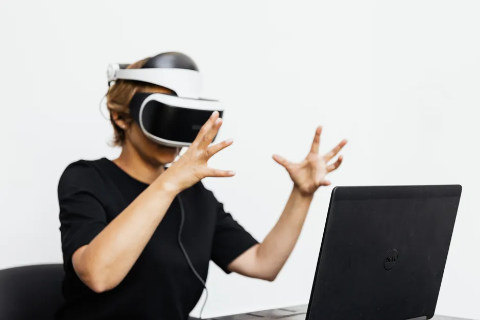 Adult using VR headset and laptop for a virtual reality experience indoors.