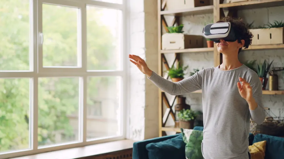 Acrophobie : la réalité virtuelle réduit la peur des hauteurs, sans bénéfice supplémentaire de l’iTBS An adult woman wearing VR goggles, interacting with virtual reality in a modern indoor setting.