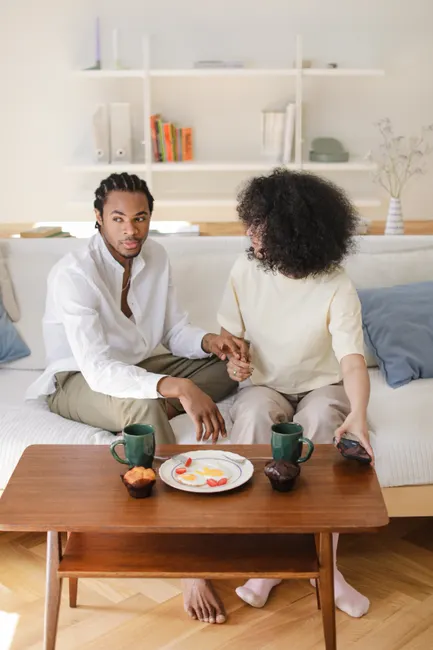 An African American couple enjoying a cozy afternoon at home, sitting together on a couch.