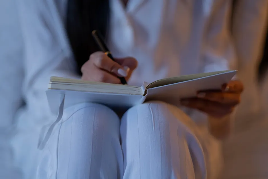 An intimate close-up of a person writing in a notebook, capturing a nighttime writing session.
