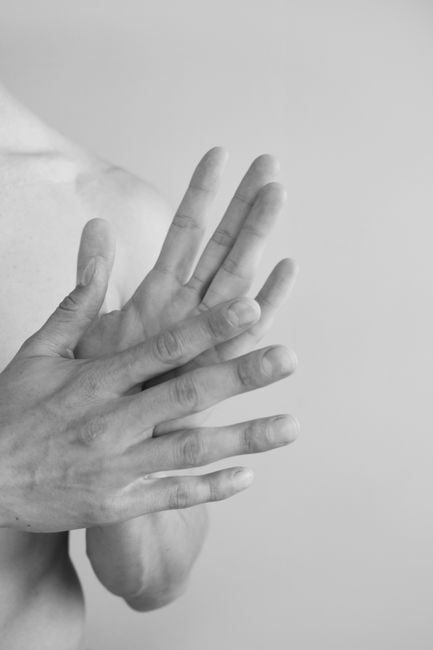 Artistic black and white close-up of a man rubbing his hands, captured in a studio setting.