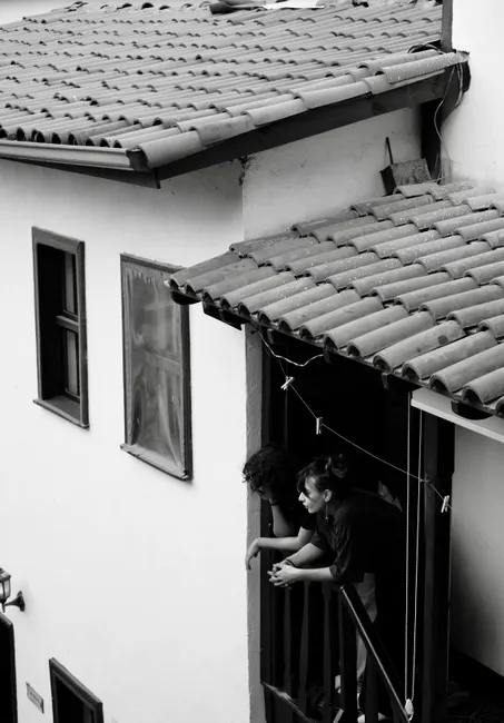 Black and white image of two people on a balcony, creating a moody atmosphere.