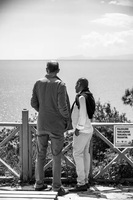 Black and white image of two people standing on a cliff, gazing at the ocean.