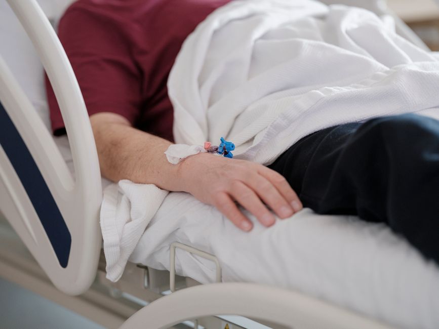 Schizophrénie en 2026 : quatre pistes de recherche à suivre Close-up of a patient's hand with an IV drip lying on a hospital bed.