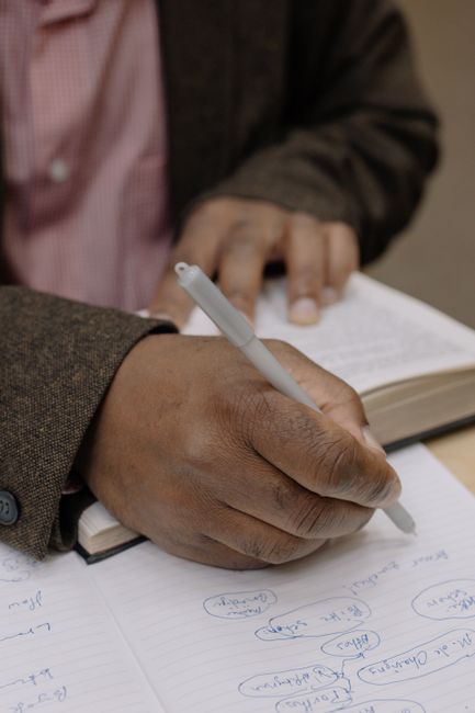 Close-up of a person writing notes during study session, showing focused academic preparation.