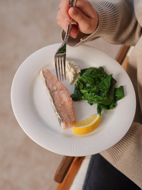 Close-up of a salmon dish with spinach and lemon on a plate, perfect for a healthy lunch.