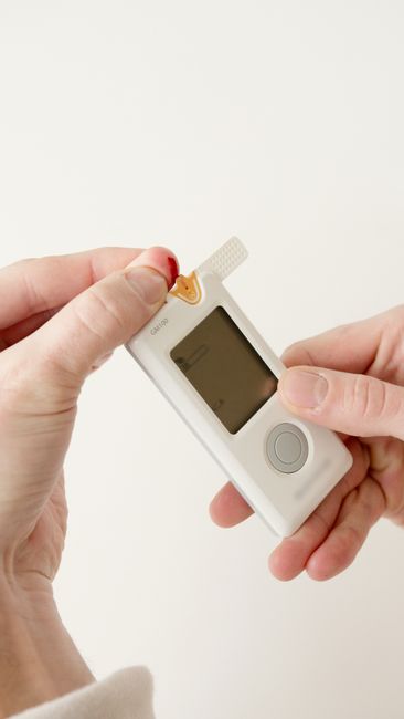 Close-up of hands using a glucometer for diabetes monitoring. Testing blood glucose levels.