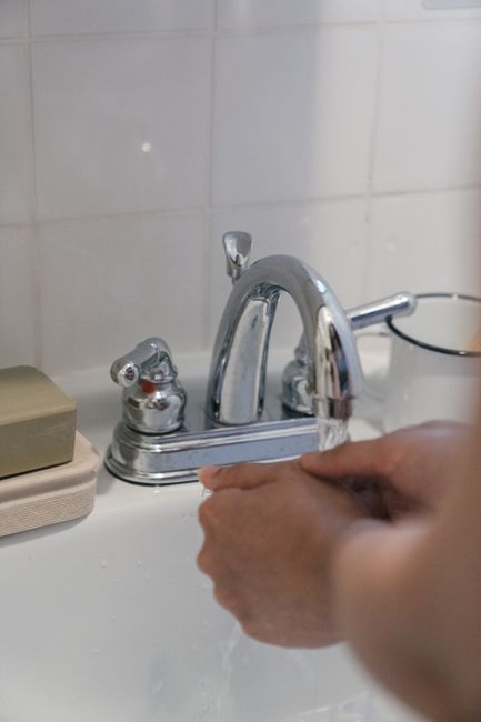 Close-up of person washing hands under a running faucet, emphasizing hygiene and sanitation.