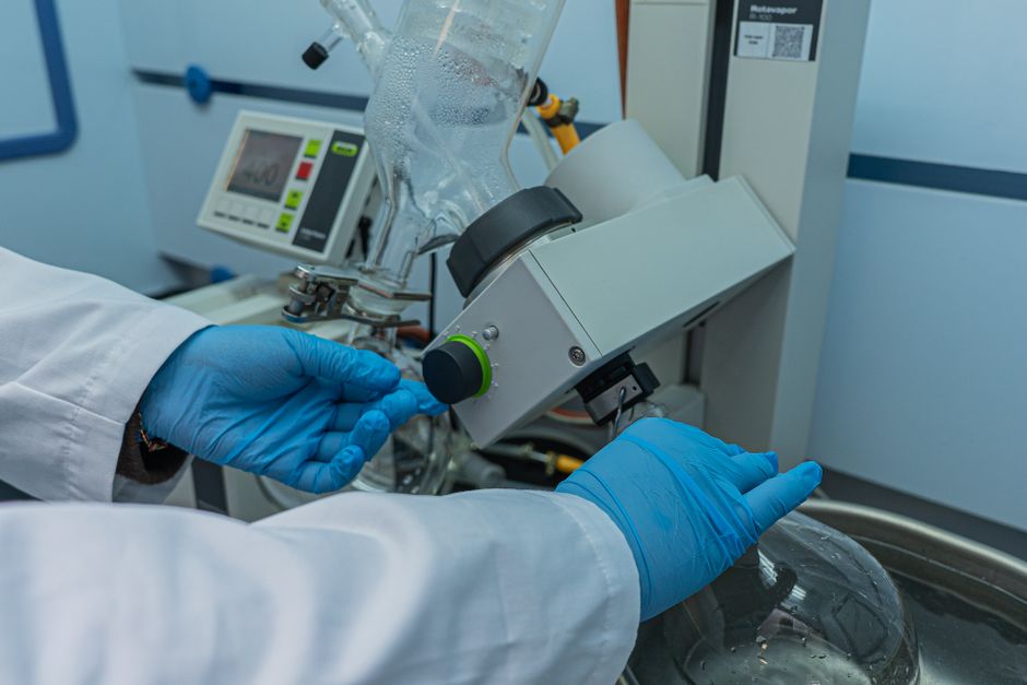Close-up of scientist controlling rotary evaporator in laboratory, showcasing technology and precision.