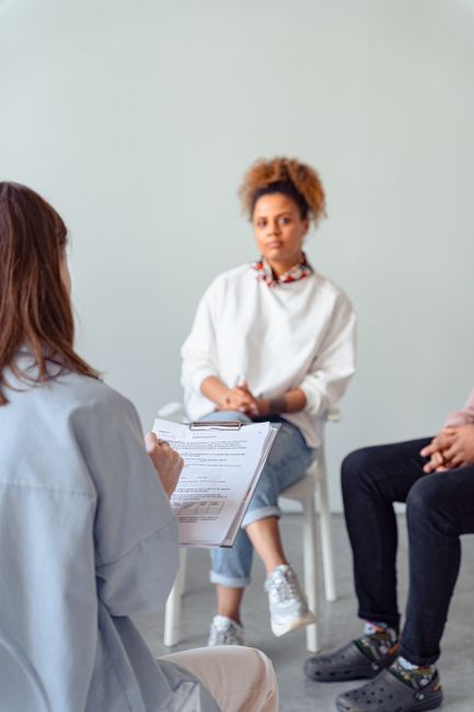 Counselor and diverse woman in a therapy session discussing mental health.