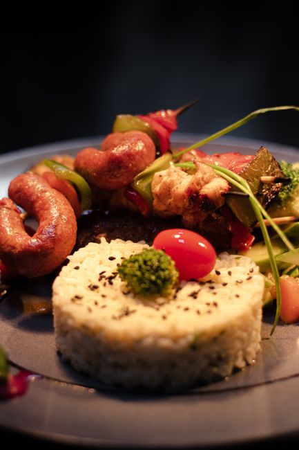 Delicious gourmet meal of seasoned rice and skewered meats garnished with vegetables.
