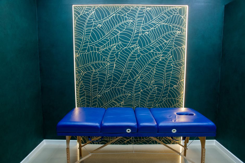 Discover a luxurious massage room featuring a blue table and intricate wall design.
