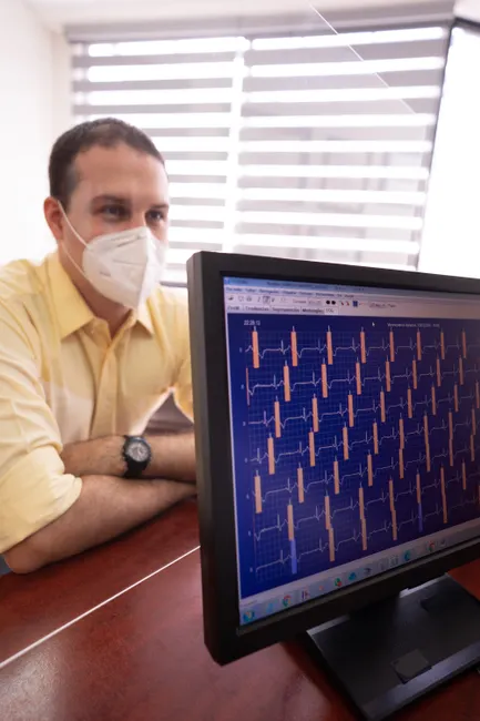 Doctor analyses heart monitor readings on a computer screen in a healthcare setting.