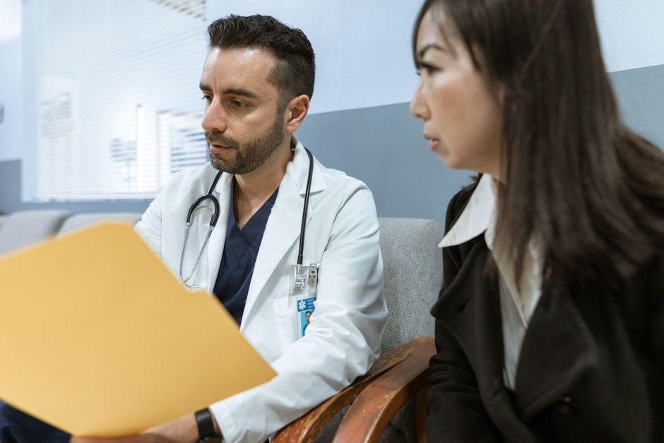Comorbidité psychiatrique : suivre la chronologie des symptômes Doctor discusses health records with a patient in a clinical setting.