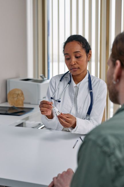 Doctor with stethoscope consulting patient, holding medication in office setting.