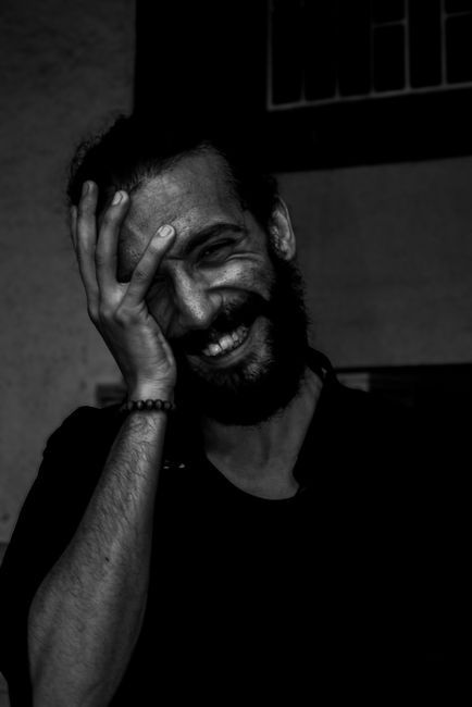 Emotive black and white portrait of a smiling man with hand on face, showcasing raw emotion.