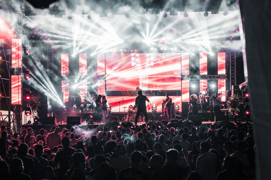 Energetic live music concert featuring performers on a vibrant stage, captivating a large audience.