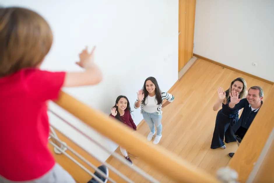 Family waving up at a person in a modern indoor setting, conveying warmth and connection.