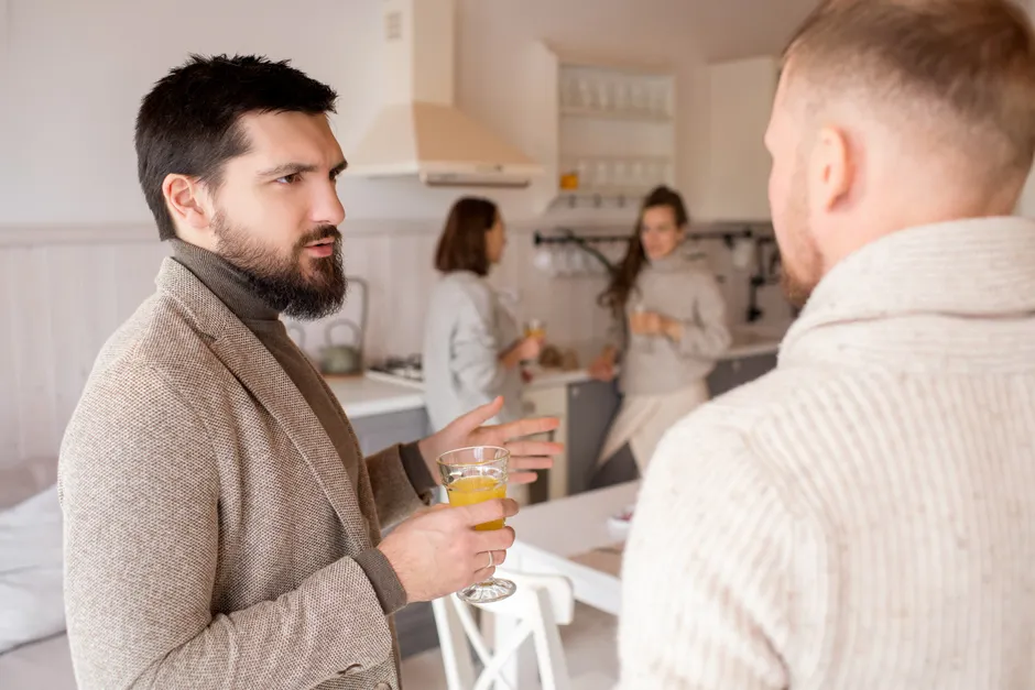 Friends having a casual conversation and drinks in a modern kitchen.