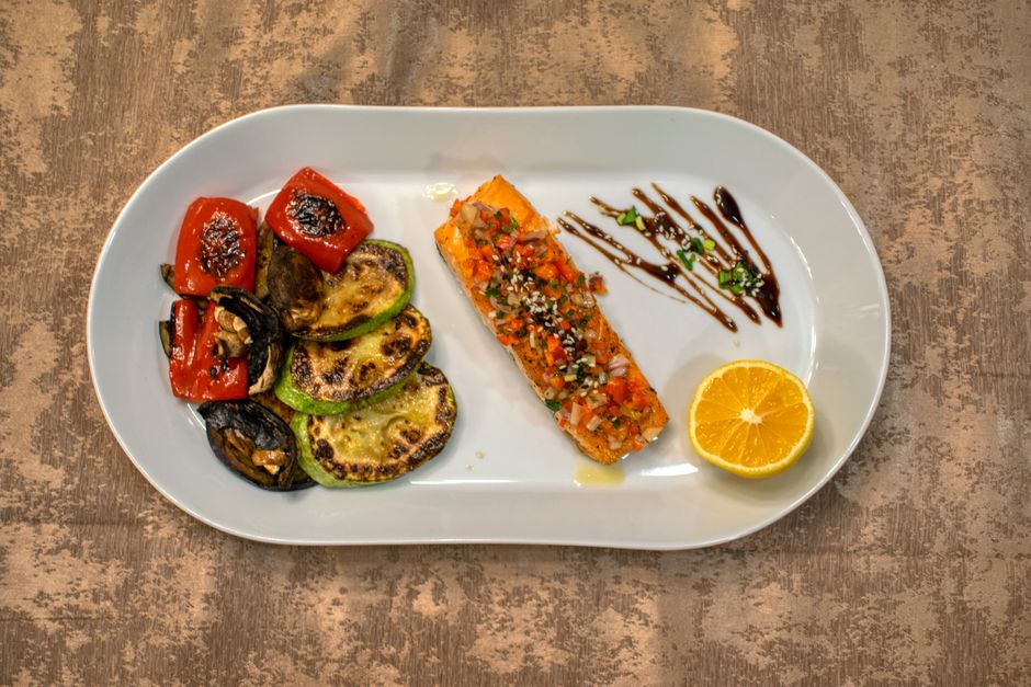 Schizophrénie et alimentation : que privilégier et que limiter? Gourmet grilled salmon served with roasted vegetables and lemon slice on a white plate.
