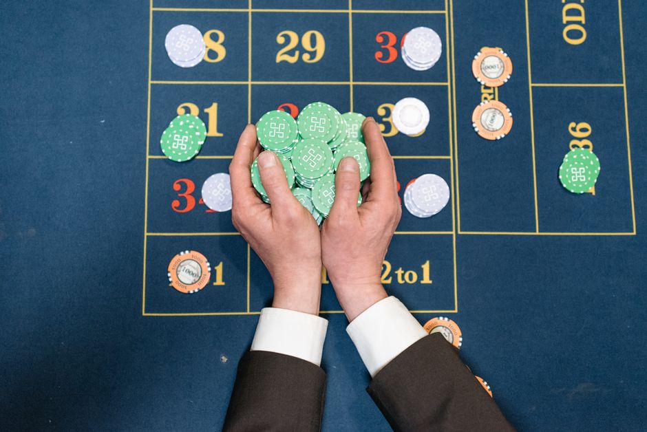 Addiction aux jeux d’argent : pourquoi arrêter de parier devient si difficile Hands in a suit holding poker chips on a casino gaming table.