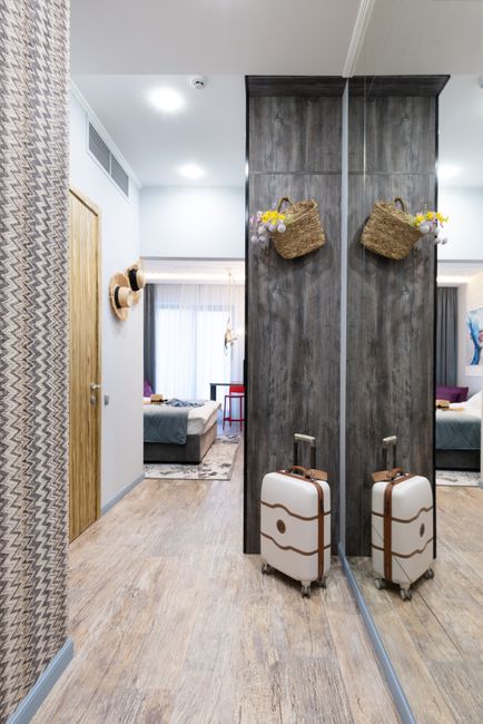 Luggage placed near wall in long corridor of modern hotel room with decoration on wall and bedroom in distance during travelling