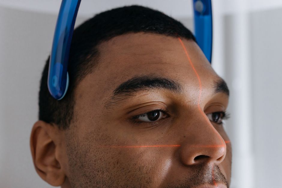 Man undergoing a dental CT scan with laser alignment in a clinic setting.