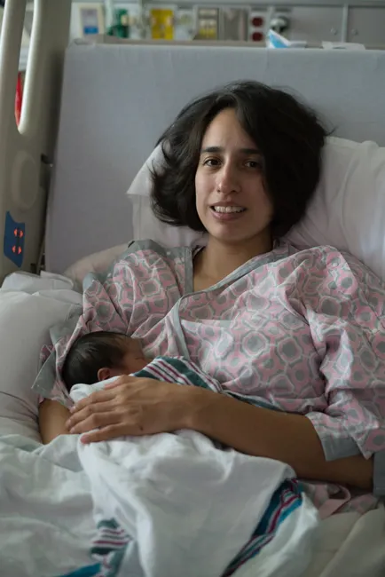 Mother lovingly holds newborn in hospital bed, capturing a serene and joyful postpartum moment.