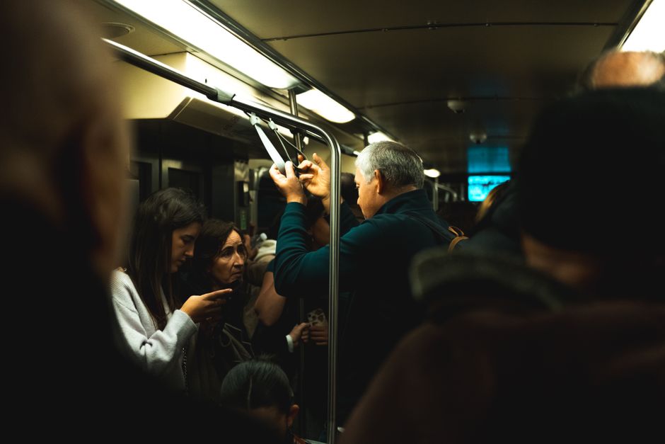 Passengers commuting in a crowded subway train, illuminated by overhead lights.