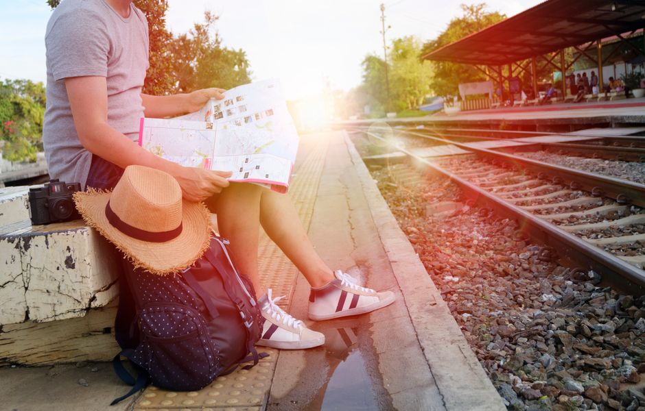 Bipolarité et attaques de panique : sortir de la peur de la peur Person sitting at train station platform reading map, embracing travel adventure.