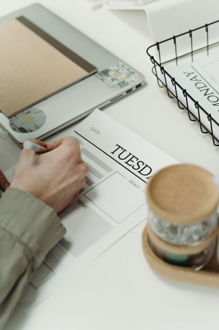 Person writing in a planner to organize weekly tasks and schedule.