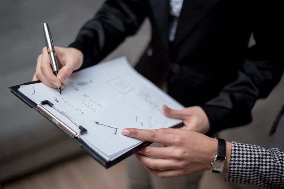 Professionals discussing notes on a clipboard during a business meeting.