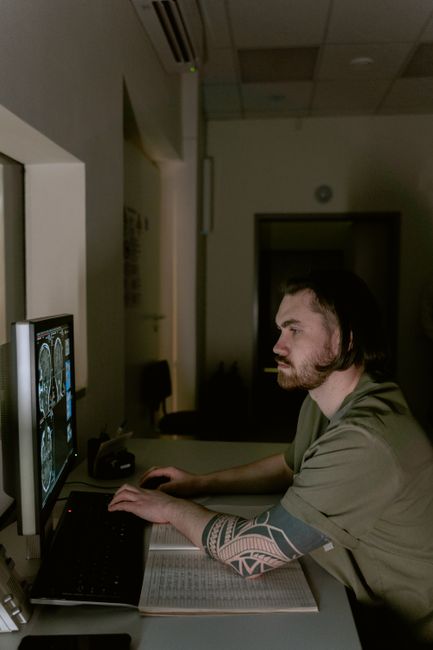 Radiologist examining brain CT scans on a computer monitor in a dimly lit medical office.